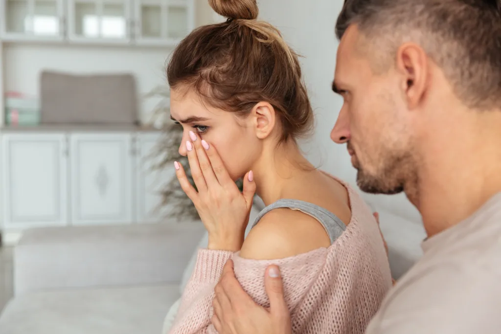 Back view of Careful man sitting on couch and calm down his upset girlfriend which crying at home